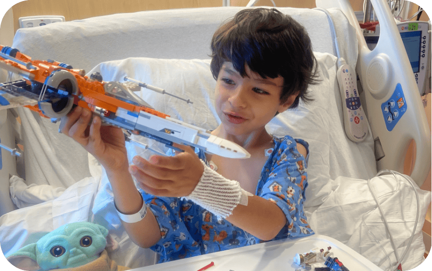 Young boy playing with rocket ship in hospital bed